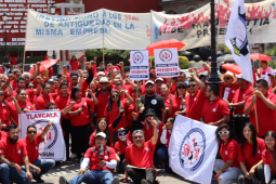 A large crowd of SINTTIA members in red shirts hold banners celebrating May Day