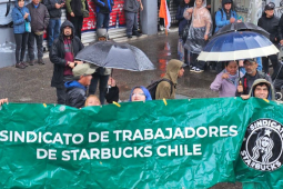 Five workers in the rain hold a green banner that says Chilean Starbucks Union in Spanish