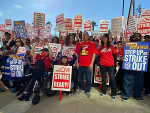 A crowd of 80 stands looking at the camera with red and white signs saying “CFA Strike Ready” 