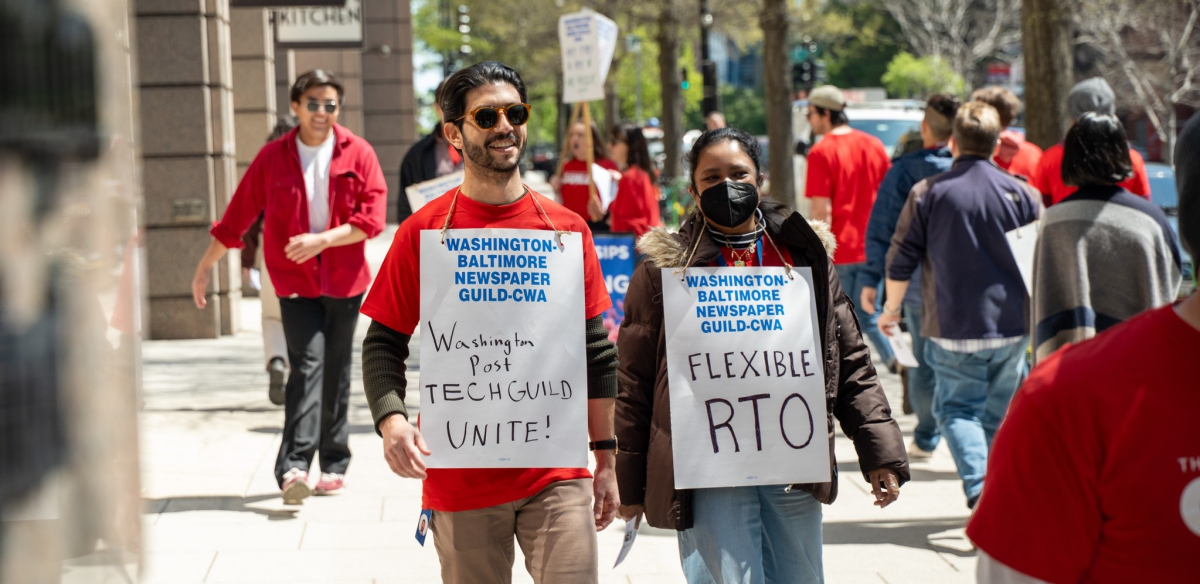 Workers in red shirts march outside the Washington Post's office, carrying signs with slogans including "Flexible RTO" (which stands for return to office) and Washington Post Tech Guild Unite!