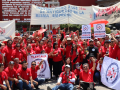 Una gran multitud de miembros de SINTTIA con camisetas rojas sostienen pancartas celebrando el Primero de Mayo.